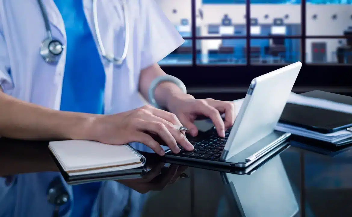 A physician using a laptop to enter patient data, illustrating the integration of AI medical scribe solutions in healthcare.